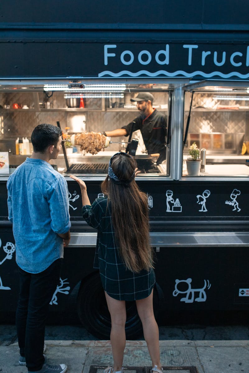 Man and Woman Standing in Front of the Food Truck