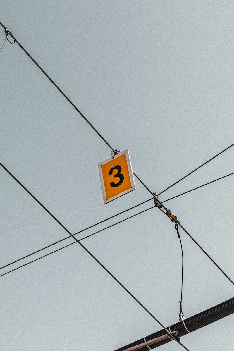 yellow 3 signboard hanging from cable